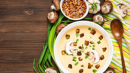 Delicious cream soup, made of mushrooms with croutons on a wooden background. Top view. Copy space.