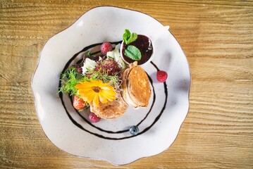 Fried Shepherd cheese with cranberry on a plante. Dinner appetizer on a wooden table. Traditional polish cuisine