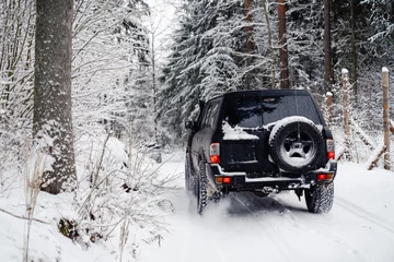 Foto op Aluminium SUV car driving in a snowy winter forest road. © RasaBasa