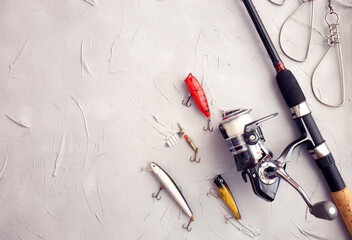 Fishing equipment composition. Rod spinning, wobblers on a gray background. Fishing concept for...