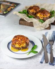 Cutlet baked with cheese, spinach and potatoes. on a white plate