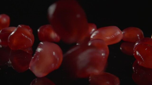 Pomegranate grains pouring down on the black background.