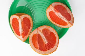 Grapefruit slices on a green plate on a white background close-up