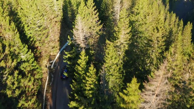4K Aerial view of a blue sedan car driving on the curved road from the Romanian Mountains Transbucegi