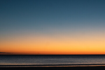 Last rays of sun at sunset and its reflection in the sky and in the sea