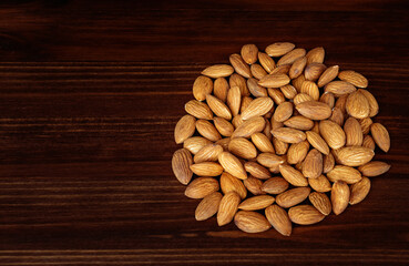 Heap of almonds against dark rustic wooden background