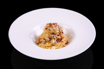 Dish of Spaghetti alla Carbonara, typical italian recipe of pasta with guanciale, egg ad pecorino romano cheese on white plate isolated on black background