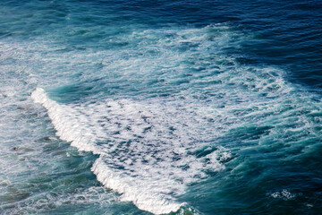 Fototapeta na wymiar Oceanic deep blue waves with foam shot from above, power of nature background