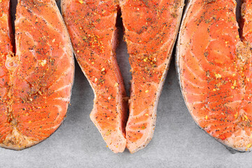Red salmon fish steak in spices on white parchment paper