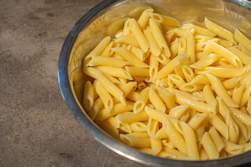 Cooked pasta penne in a bowl to prepare cooking in the kitchen. Close-up photo. Space for text. Foods concept