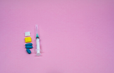 blue yellow pills with syringe on pink background