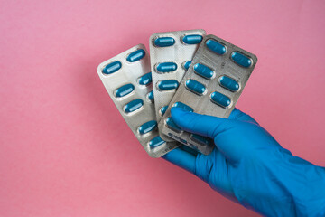 girl with blue latex gloves holding blisters of blue pills in hand