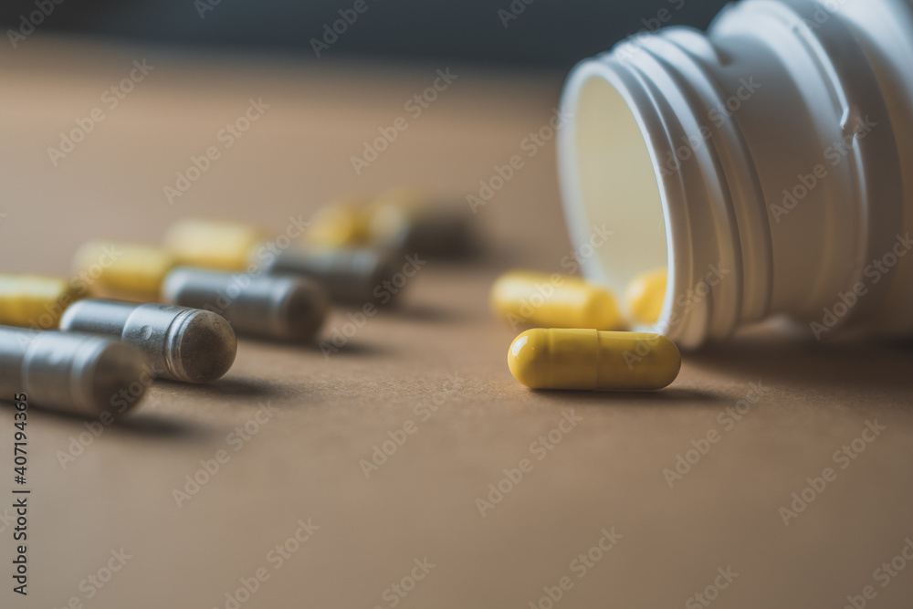 Wall mural bottle of medicinal yellow and brown pills on a beige brown background