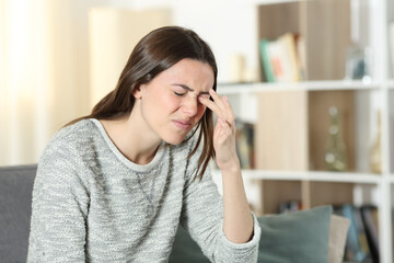Woman scratching itchy eye at home