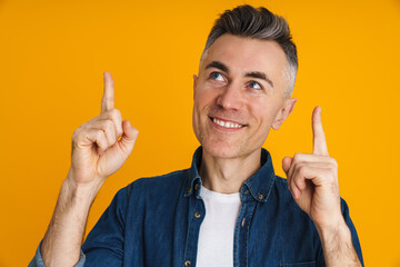 Happy handsome man smiling and pointing fingers upward