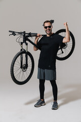 Excited rider man making winner gesture while posing with his bicycle