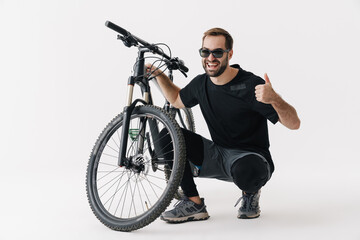 Happy rider man showing thumb up while posing with his bicycle