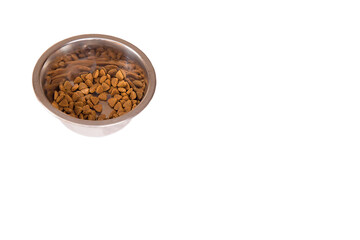 Dry food is poured into a metal bowl. Food for pets. White background. Copy space.