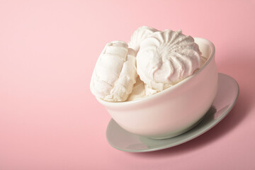 Side view of Russian traditional marshmallow dessert zefir (zephyr) souffle served on white and gray plates on pastel pink background. Similarly with Meringue Dessert. Copy space image
