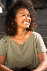 Portrait smiling young woman sitting outside looking away