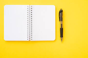 Notebook with ring binder with pen, isolated on yellow backdrop with copy space. Concept of writing.