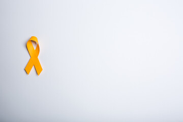 Orange handmade awareness paper ribbon on white background.