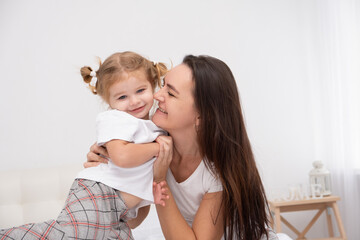 adult mother hugging her little daughter at home, having fun.