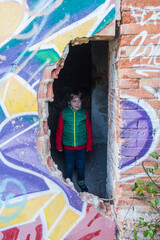 Five year old boy in a red jacket and green vest, enters an abandoned house