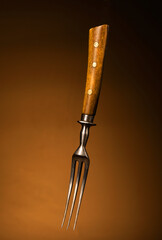 old fork with a wooden or bone handle on a brown background.