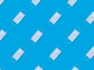 Many medical masks on a blue background cover the mouth and nose to protect against viruses and bacteria. Epidemic concept. Regular pattern, flat lay.