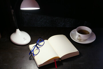 open notepad and table lamp at night 