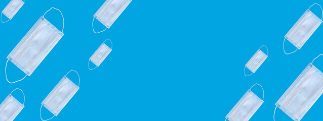 Many medical masks on a blue background cover the mouth and nose to protect against viruses and bacteria. Epidemic concept. Regular pattern, flat lay.