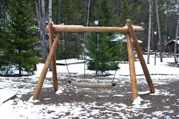 At the beginning of winter, a wooden swing in a snow-covered national park.