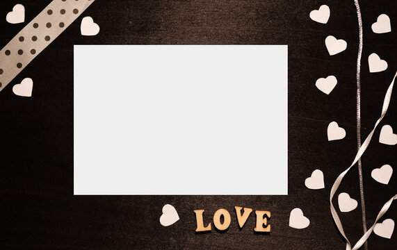 Valentines day background on vintage black wood surrounded by white hearts, the word love and with ribbons and laces