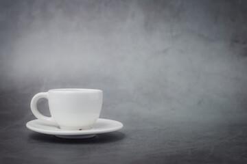 White cup of coffee with saucer with copy space on dark background for drinks and beverage concept