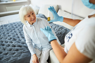 Obraz premium Excited female pensioner looking at the nasal drops