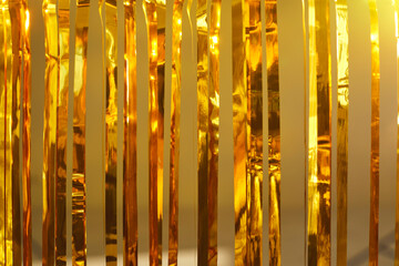Fun party decor concept. Festive background of shiny metallic tinsel strands. Closeup of gold foil...