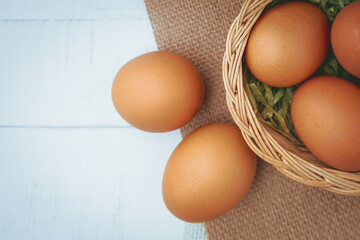 Eggs in the wicker basket on white wooden background for healthy food concept