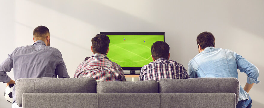 Four Men Friends Sitting Backwards On Sofa At Home And Watching Soccer Football Match Game Sport On Television Together. Leisure, Hobby, Entertainment For Male Company Concept