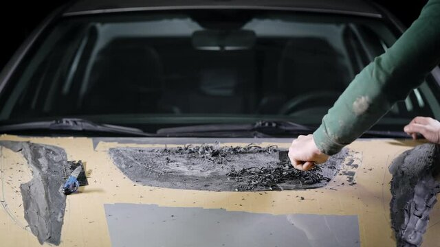 master of car tuning is creating model of detail for hood by modeling clay in garage, using plastic knife