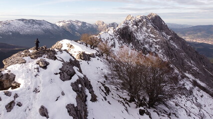 climber reaching a mountain summit in winter (aerial video)