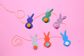 happy easter garland from paper rabbits with colored pompon tail. DIY concept and home decor