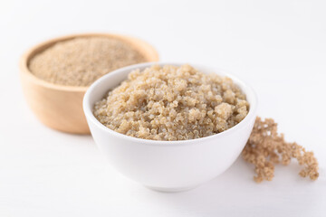 Cooked brown quinoa seeds and raw quinoa seeds in a bowl on white background, Healthy vegan food