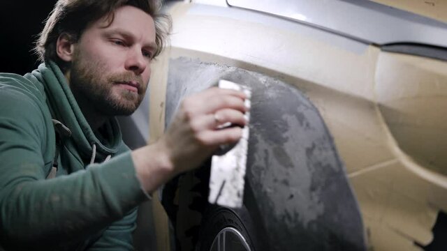 designer man is polishing plasticine billet of detail of automobile in garage, projecting of car tuning