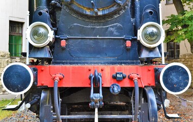 Fototapeta premium Front view of the locomotive of a red and black train on rails