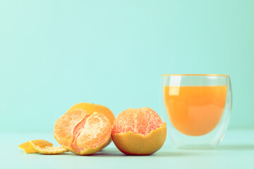 Fresh tangerine orange fruit and juice in glass on color background