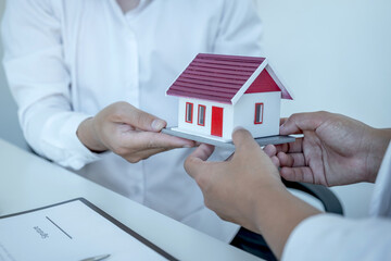 Home Model in hands, The real estate agent explains the business contract, rent, purchase, mortgage, a loan, or home insurance to the business buyer