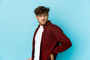 Young arab man on blue background suffering a back pain.