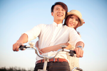 Naklejka premium The young couple riding a bicycle