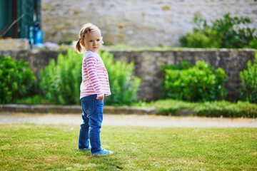 Adorable toddler girl having fun in park on a warm and sunny summer day